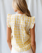 Woman wearing a yellow checkered blouse against a white background