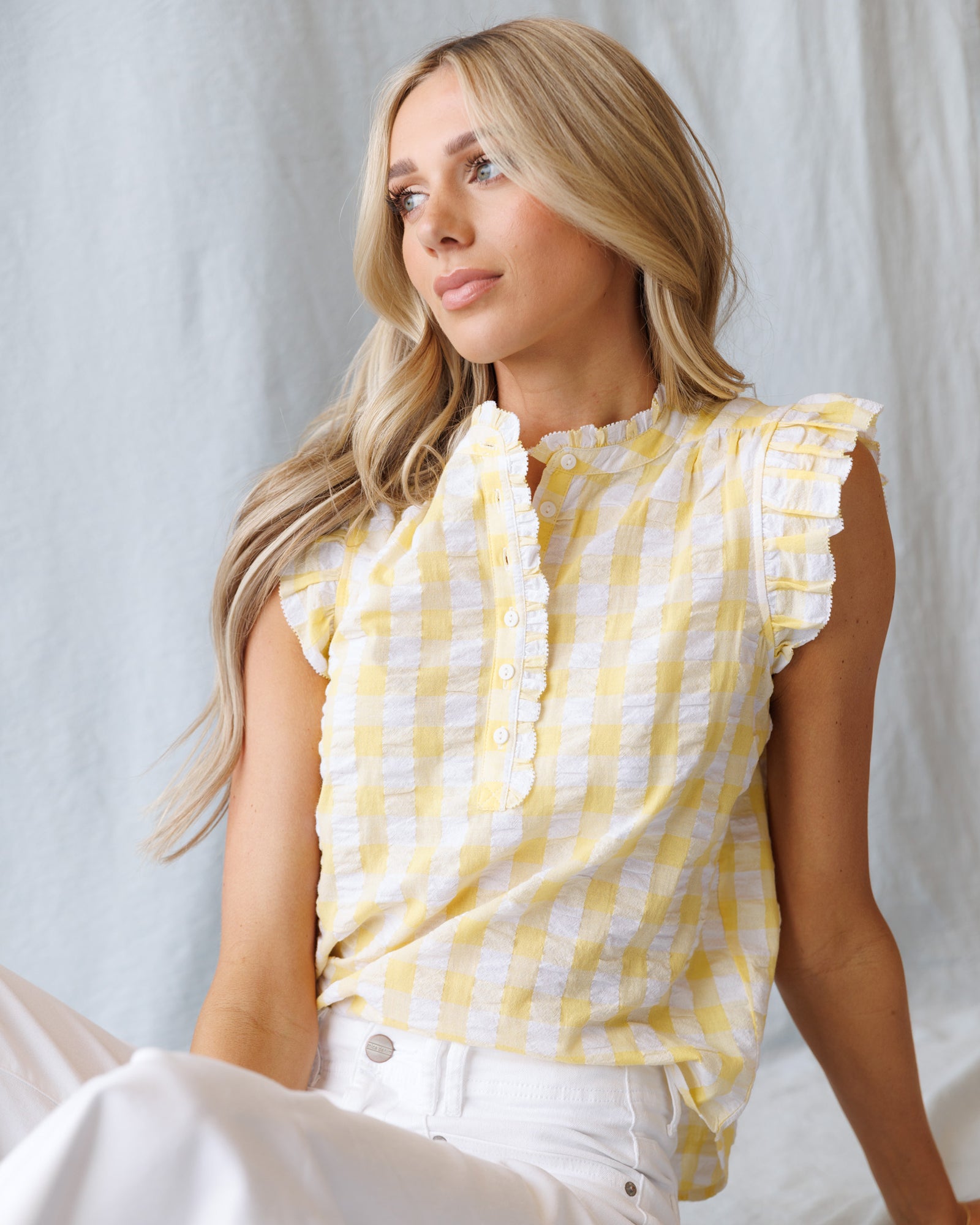Woman wearing a yellow and white checkered top against a light background