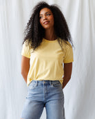 Woman wearing a yellow t-shirt and blue jeans against a white background