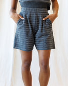 Person wearing black polka dot shorts on a plain background