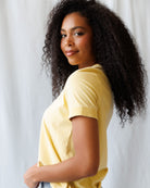 Woman wearing a yellow t-shirt against a plain background