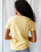 Person wearing a yellow t-shirt against a plain background