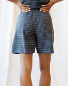 Person wearing black shorts with white polka dots on a plain background
