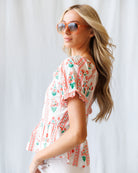 Woman wearing a floral blouse and sunglasses against a white background
