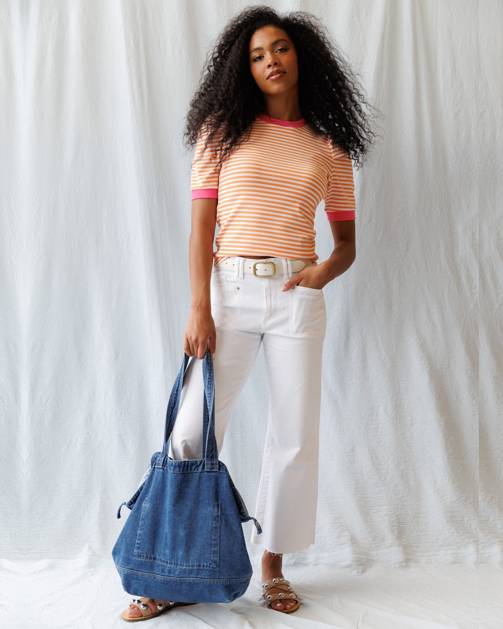 Woman holding a blue denim bag against a white background