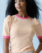Woman wearing a striped shirt with pink trim against a light background