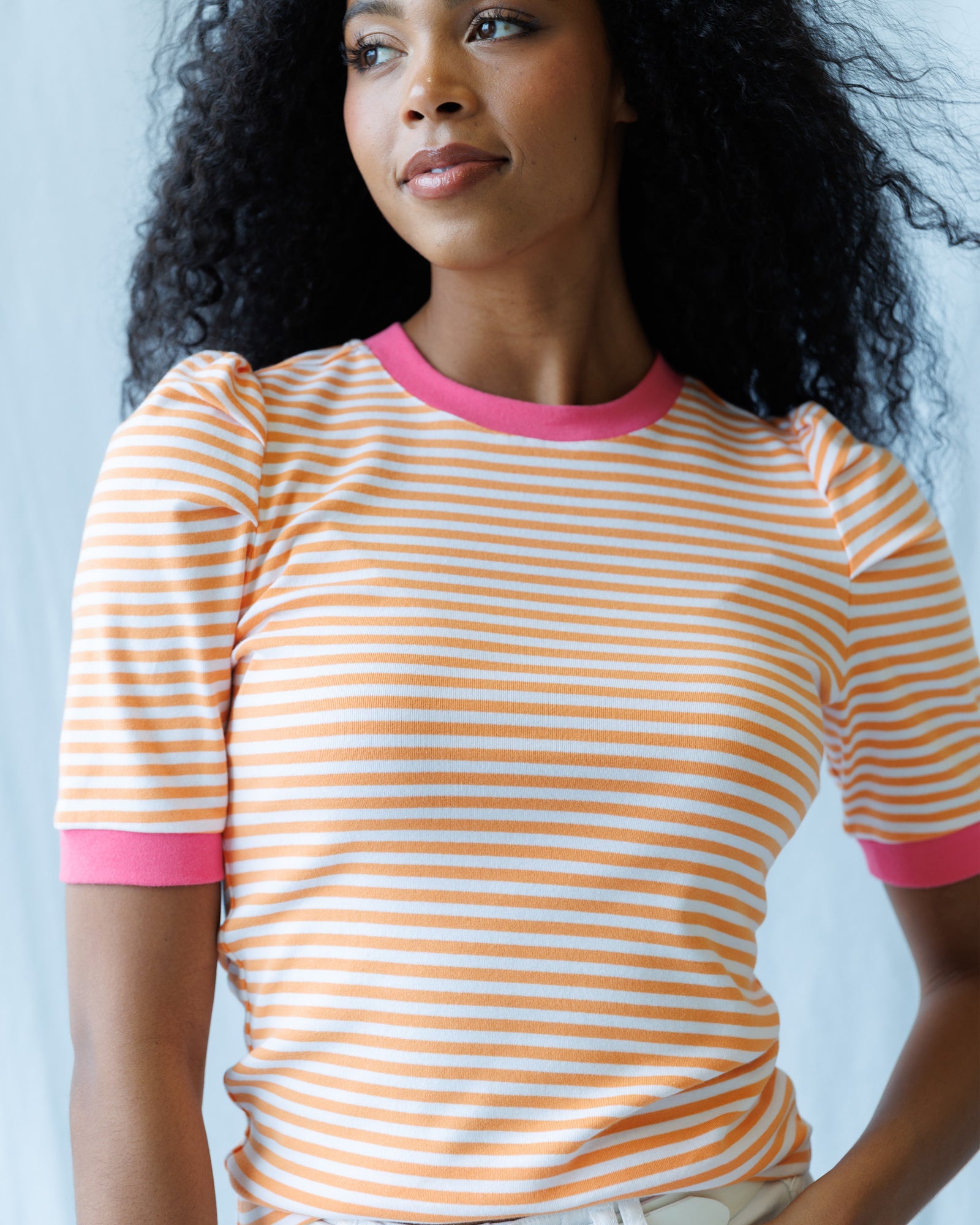 Woman wearing a striped shirt with pink trim against a light background
