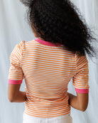 Person wearing a striped shirt with pink accents against a light background
