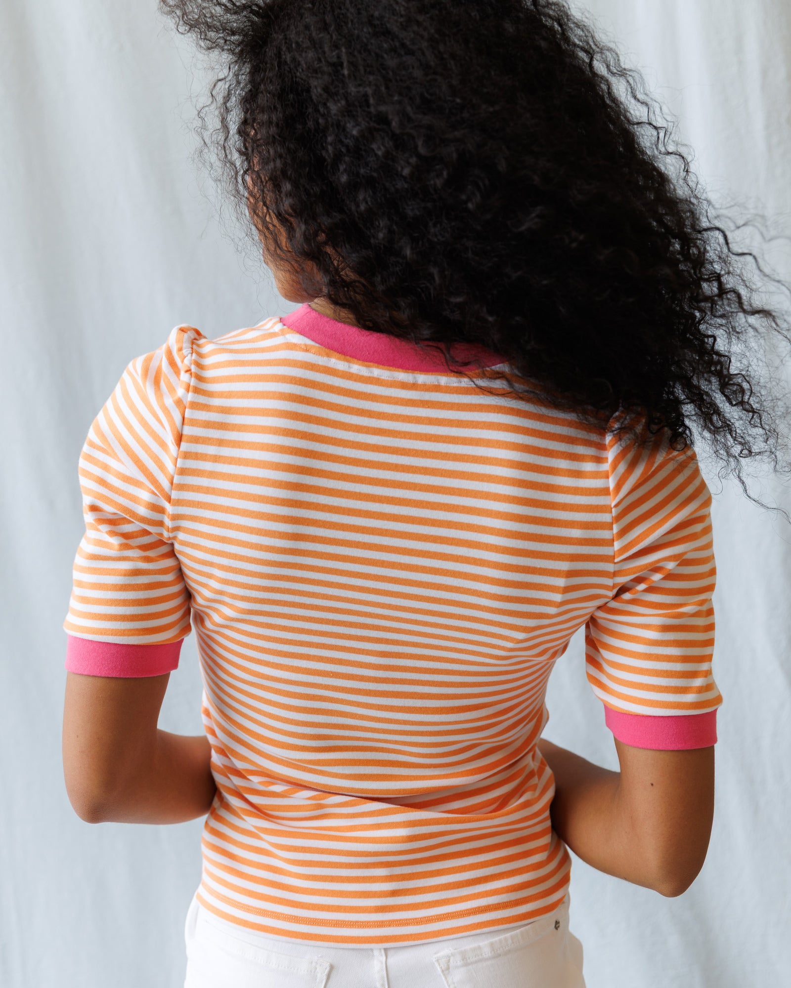 Person wearing a striped shirt with pink accents against a light background