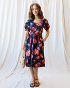 Woman wearing a floral dress against a white curtain background