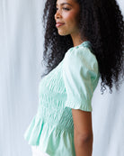 Woman wearing a light green top with a plain background