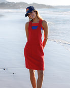 Woman in a red dress and blue cap standing on a beach