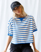 Woman wearing a blue and white striped shirt and a black cap with 'Brooklyn' text against a white background