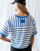 Person wearing a blue and white striped shirt with a logo on a white background