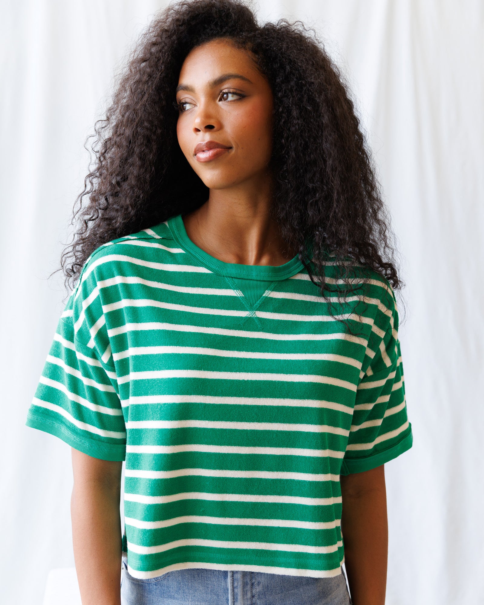 Woman wearing a green and white striped shirt against a plain background
