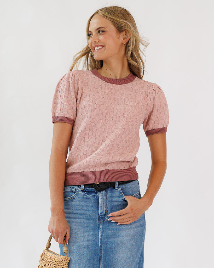 Model wearing a pink textured short sleeve pullover sweater