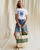 Woman holding a tote bag with flowers against a plain background
