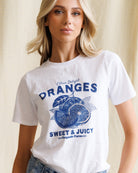 Woman wearing a white t-shirt with blue 'Oranges' graphic design.