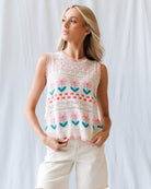 Woman wearing a sleeveless top with floral patterns against a white background