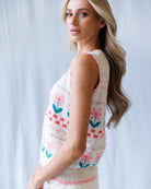 Woman wearing a sleeveless crochet top with floral patterns against a light background