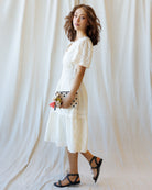 Woman wearing a white lace dress against a plain background