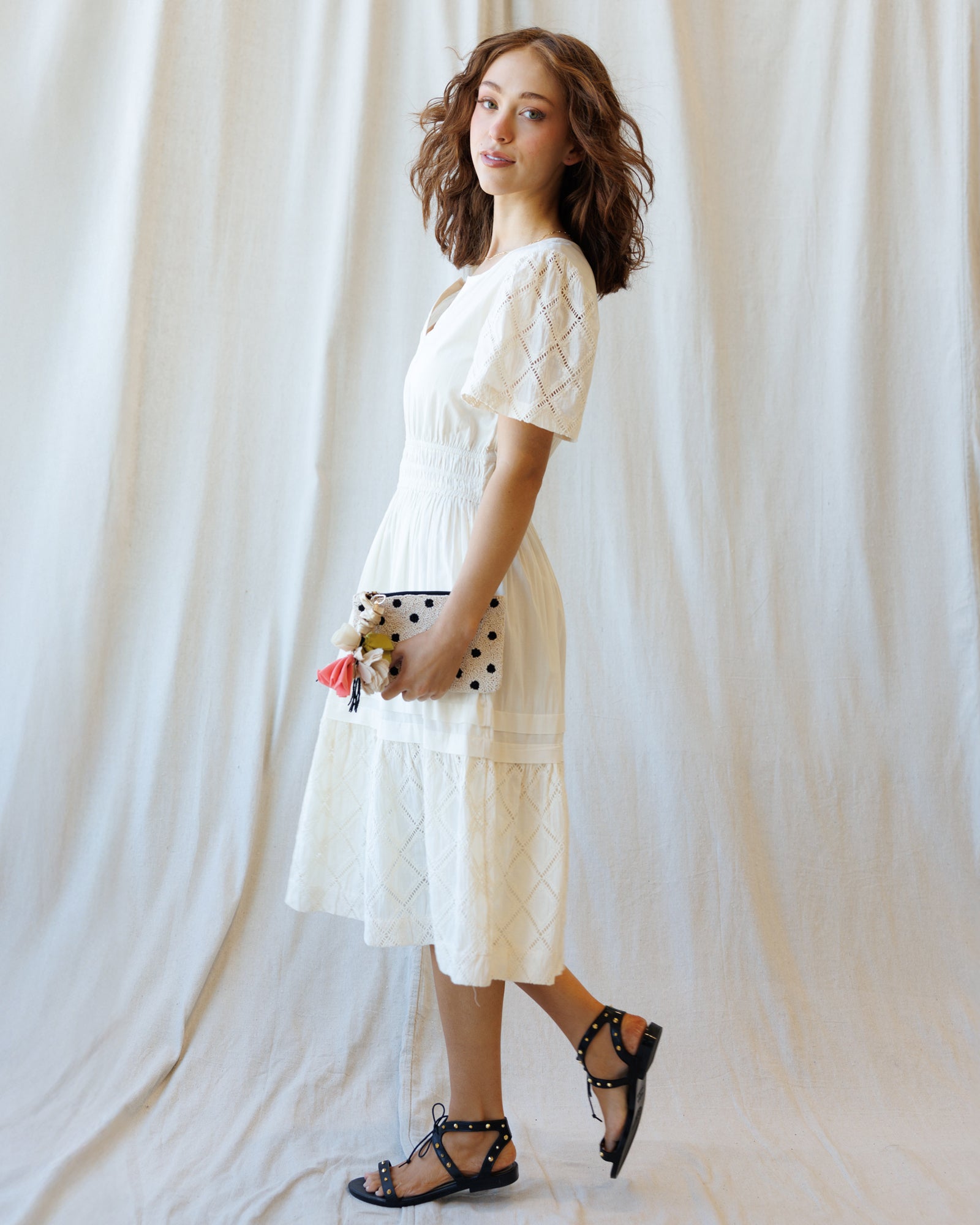 Woman wearing a white lace dress against a plain background