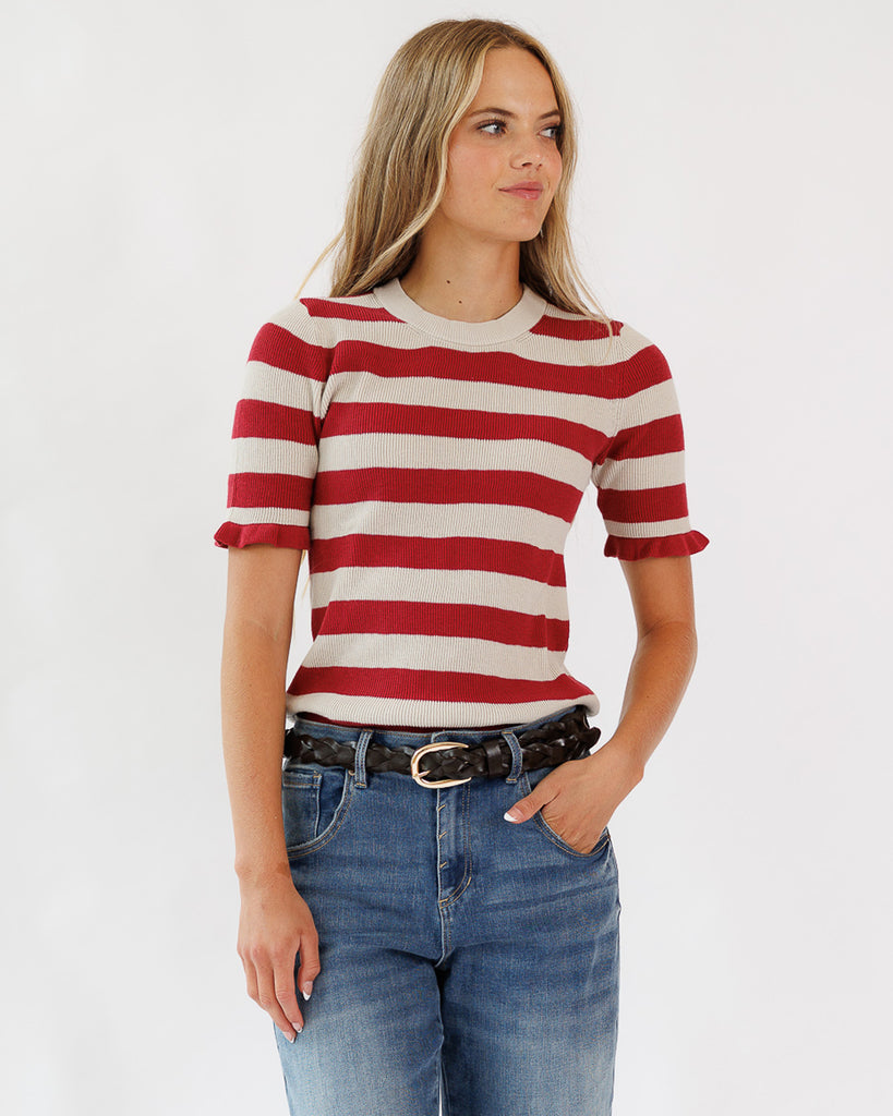 Model wearing a red and tan striped short sleeve with ruffle pullover sweater