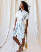 Woman wearing a striped dress standing against a plain background