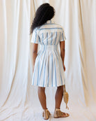Woman wearing a striped dress against a white curtain background