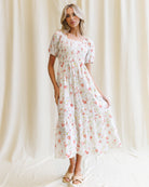 Woman wearing a floral dress standing against a white curtain