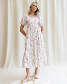 Woman wearing a floral dress against a white curtain background