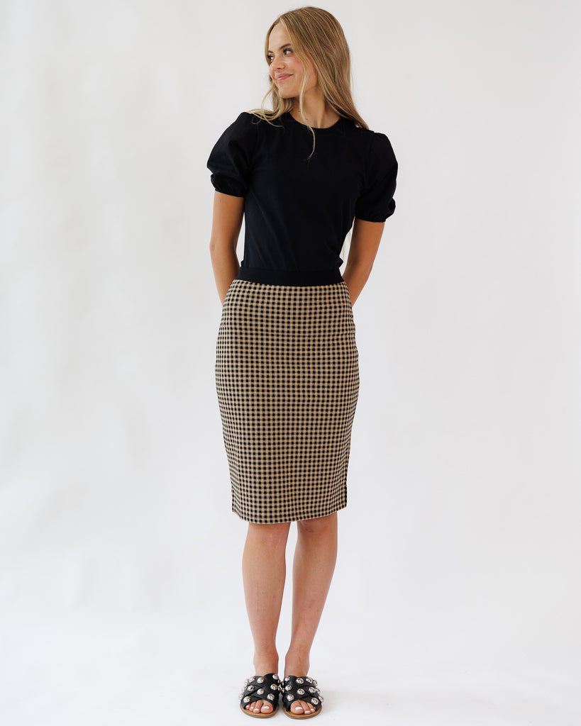 Woman wearing a black top and plaid skirt on a white background