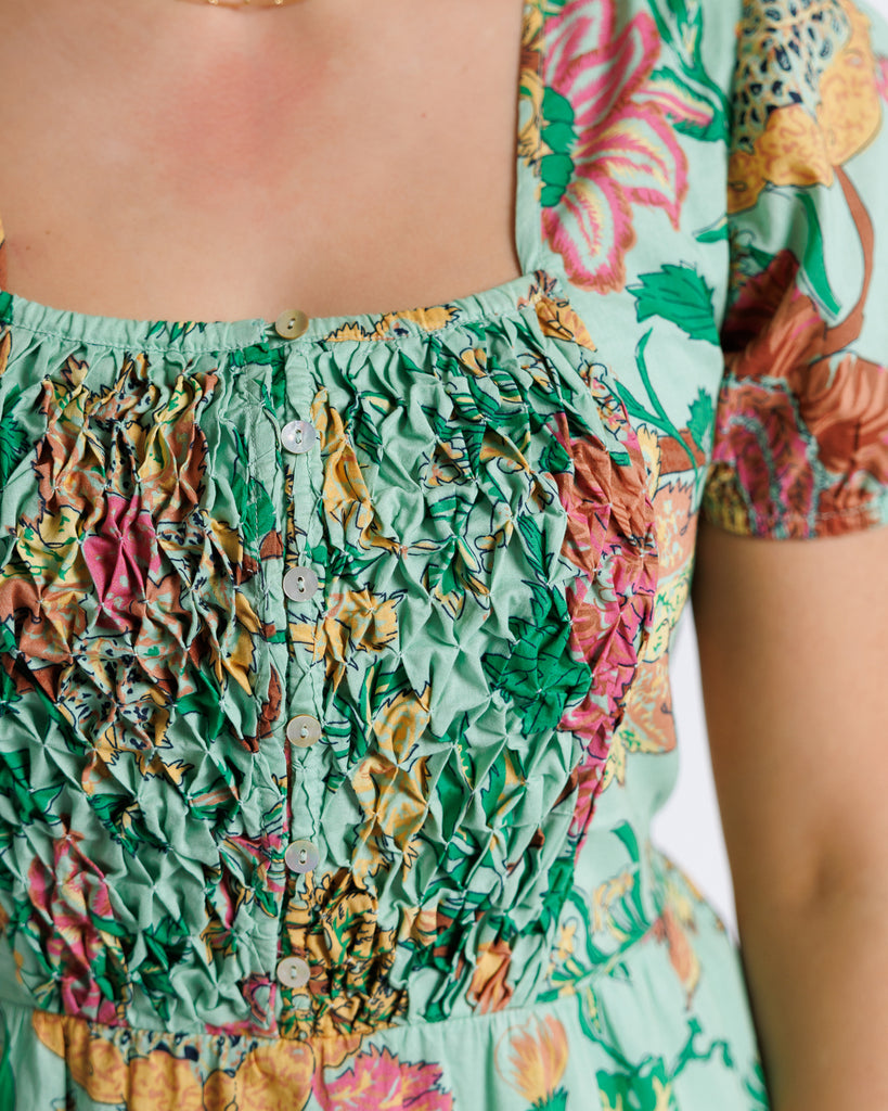 Model wearing a green floral print short sleeve, square neck, knee length dress.