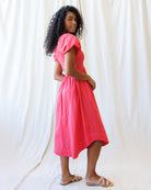 Woman wearing a bright pink dress against a white background