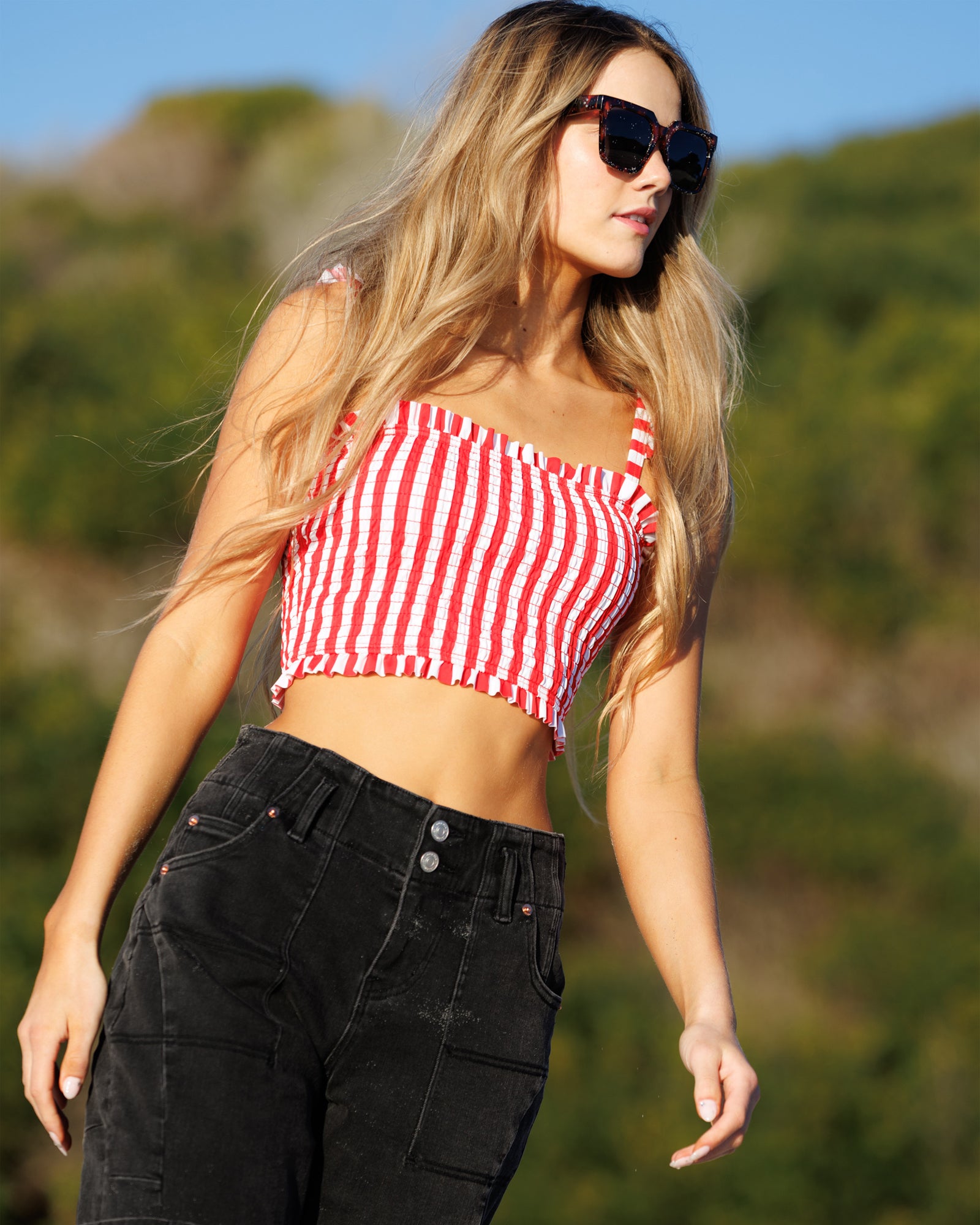 Woman wearing a red and white striped top and black pants outdoors.