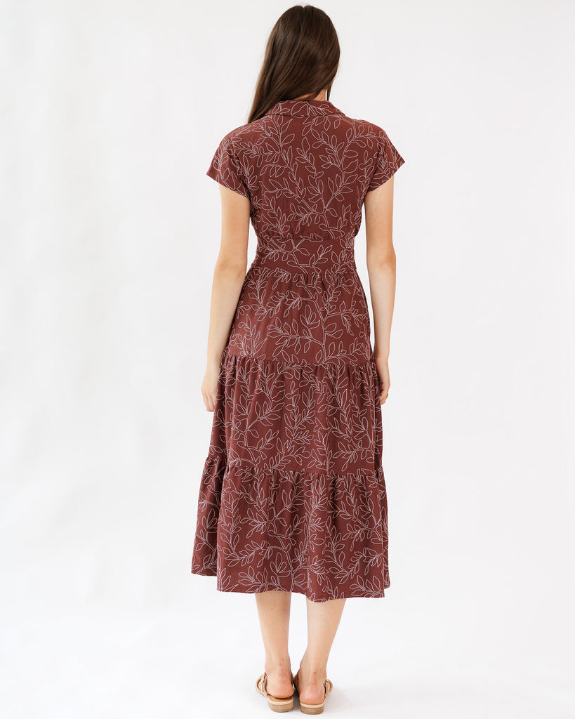 Woman wearing a maroon patterned dress on a white background