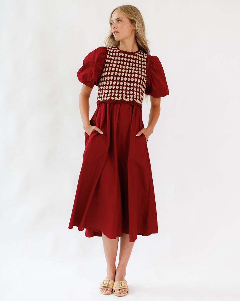 Woman wearing a red dress with a knit sweater on a white background
