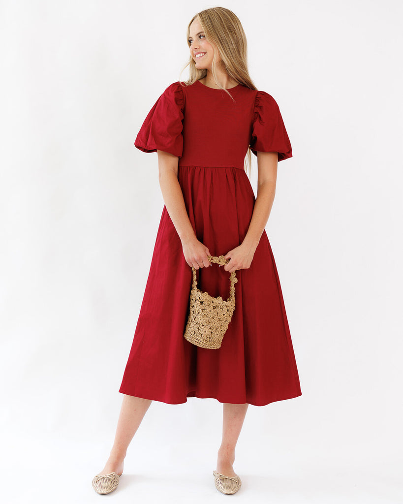 Woman wearing a red dress with puff sleeves against a white background