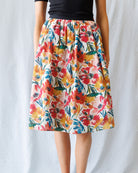 Colorful floral skirt worn by a person on a plain background