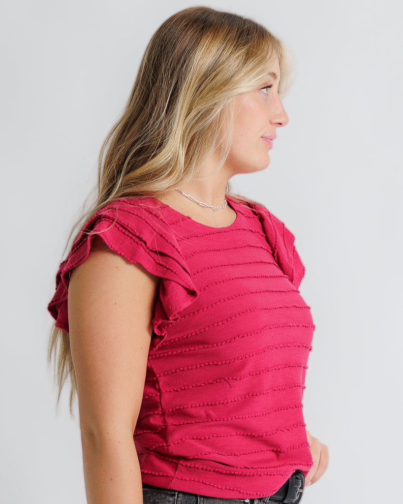 Model wearing a bright red short flutter sleeve, round neck, scallop textured top.
