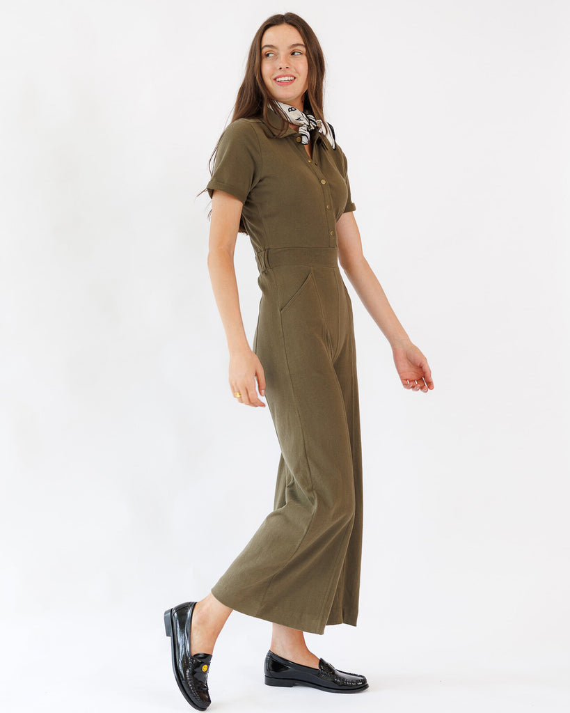 Woman wearing an olive green jumpsuit on a white background