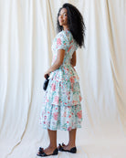 Woman wearing a floral dress against a white curtain background