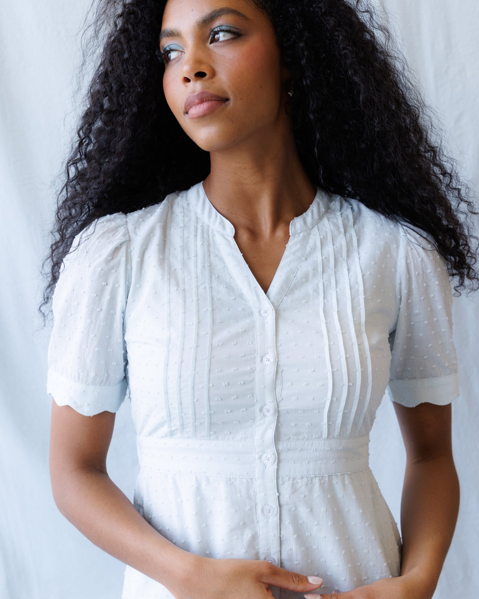 Woman wearing a light blue dress against a plain background