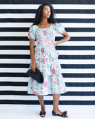 Woman in a floral dress standing against a black and white striped background