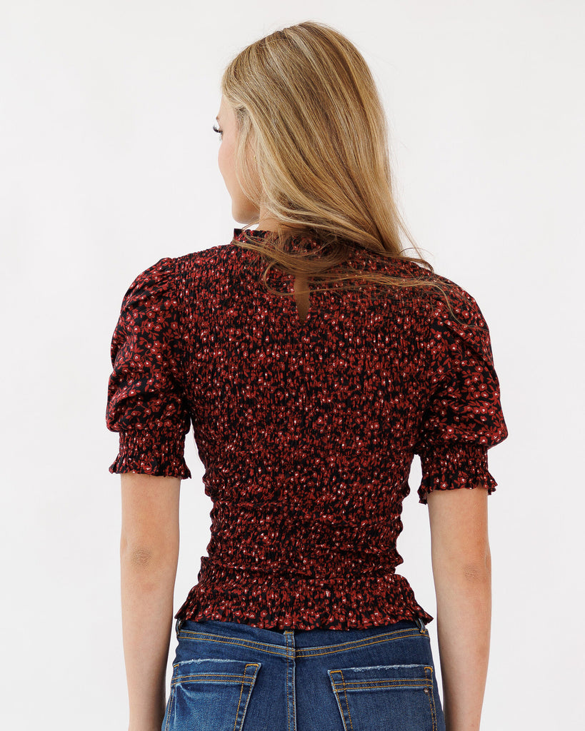 Woman wearing a red floral blouse with blue jeans on a white background