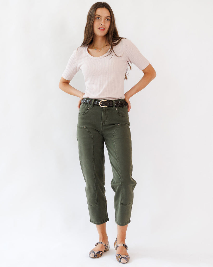 Woman wearing a white top and green pants on a white background