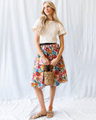 Woman wearing a floral skirt and white top against a white background