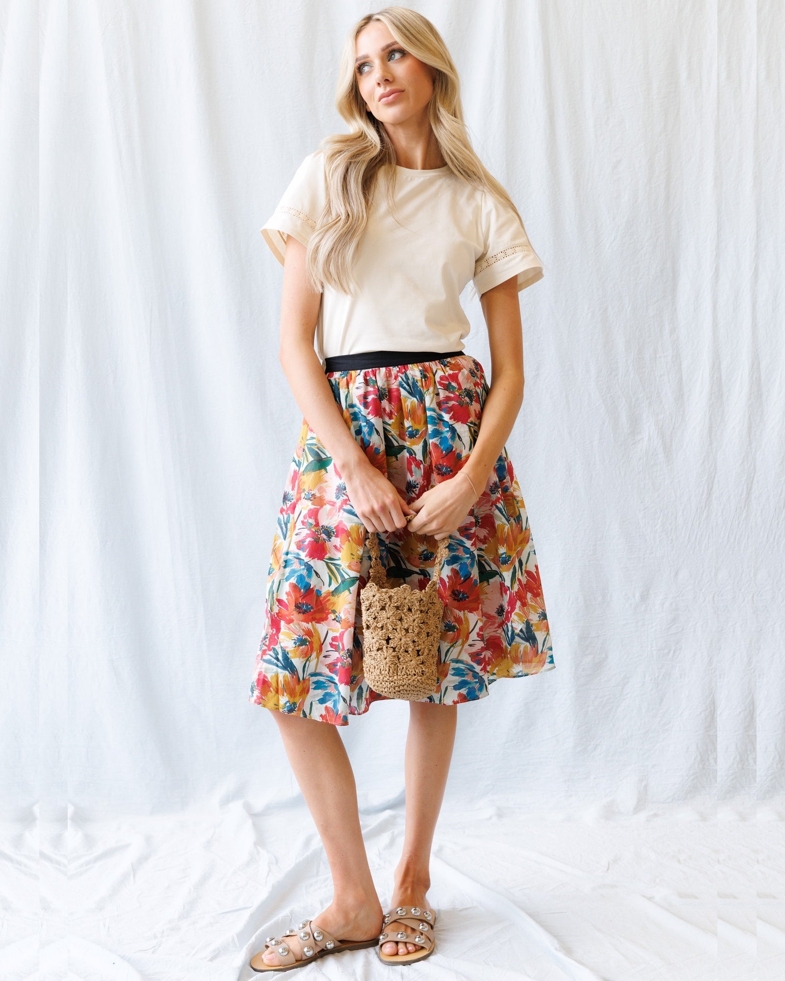 Woman wearing a floral skirt and white top against a white background