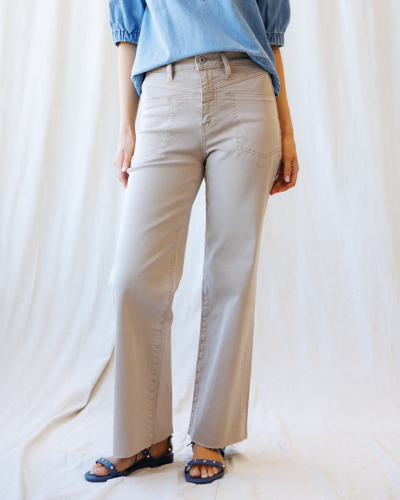 Person wearing beige pants and a blue shirt against a white background