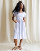 Woman wearing a purple checkered dress against a beige curtain background